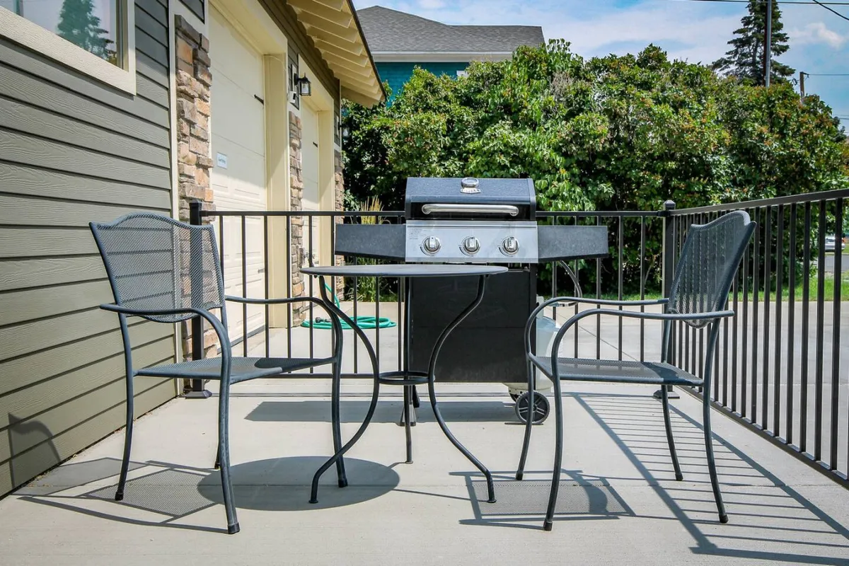 This image shows an inviting exterior patio area featuring a grill, a table, and chairs. The setup suggests a casual space perfect for outdoor dining or relaxing after exploring the city. The stonework and outdoor furniture add a cozy, approachable vibe, connecting the cottage to its urban surroundings.
