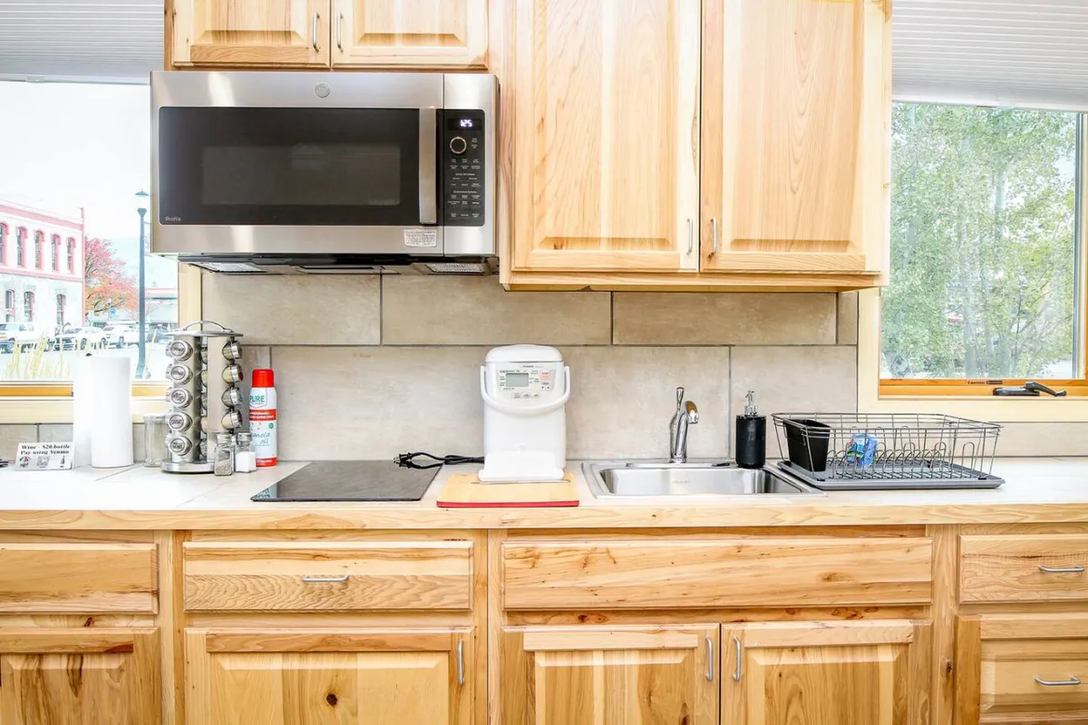 This image showcases a kitchen featuring natural wood cabinetry, modern stainless steel appliances, and clean countertops. The room is clearly designed for functionality and social connection, with plenty of prep space and a cozy, inviting mood. You can imagine guests gathering for brunch or preparing a family meal together.