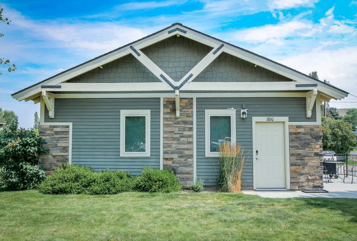 A welcoming stone-facade cottage with a double front door, asymmetrical roof, and a landscaped front yard. The warm, inviting atmosphere suggests a comfortable retreat after a day spent exploring the outdoors.